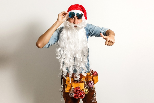 A man dressed as Santa wears a plumber's toolbelt, all ready to keep your home safe from plumbing problems this holiday season.