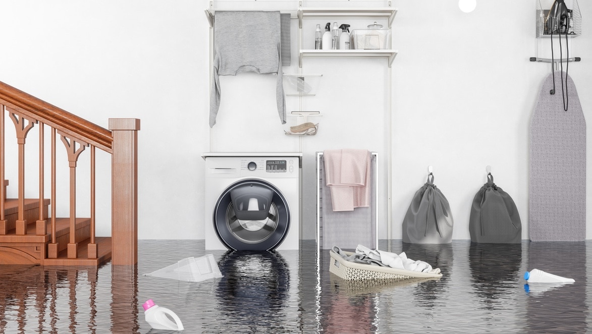 Flooded laundry room with washing machine, ironing board, and floating detergent bottles.